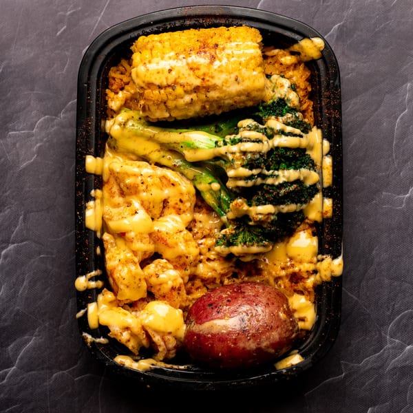Bluff City Crab seafood boil with shrimp, corn, broccoli, potato, and rice, drizzled with sauce.