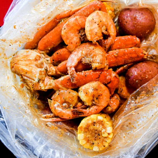 Bluff City Crab's seafood boil with shrimp, crab legs, corn, and potatoes in a plastic bag.