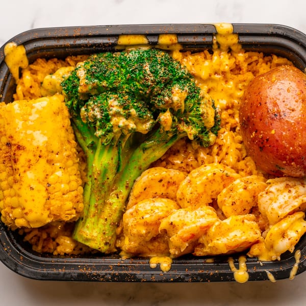 Bluff City Crab's shrimp, corn, broccoli, and potato meal in a black takeout container.