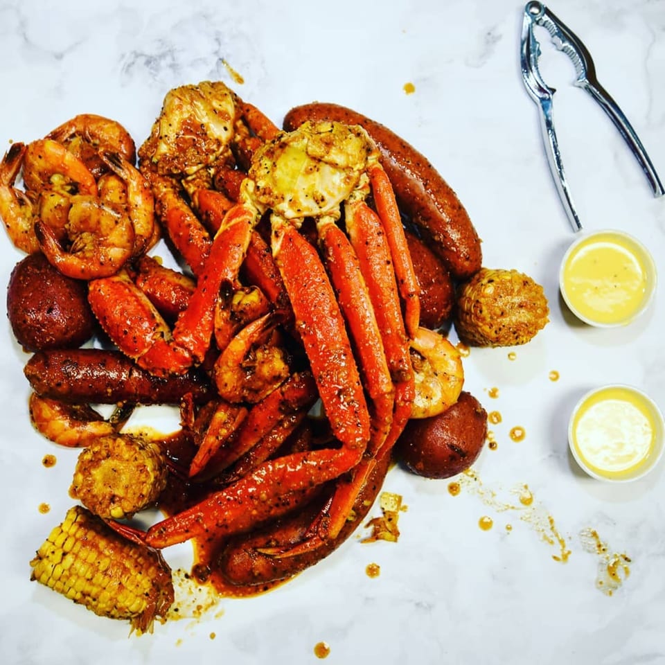 Bluff City Crab's seafood boil with crab legs, shrimp, sausage, corn, potatoes, and dipping sauces.
